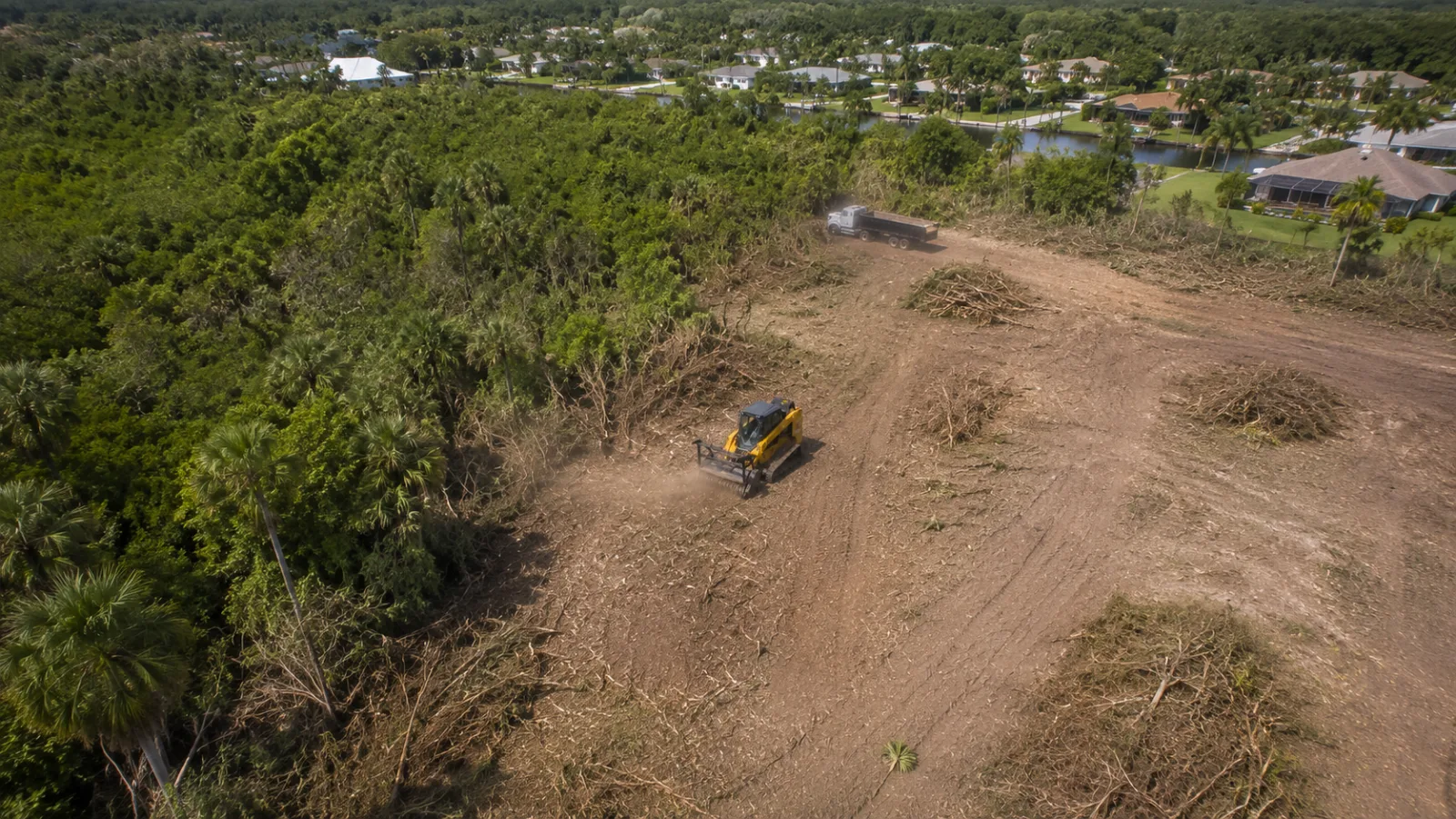 Aerial view of land clearing equipment working a wooded lot